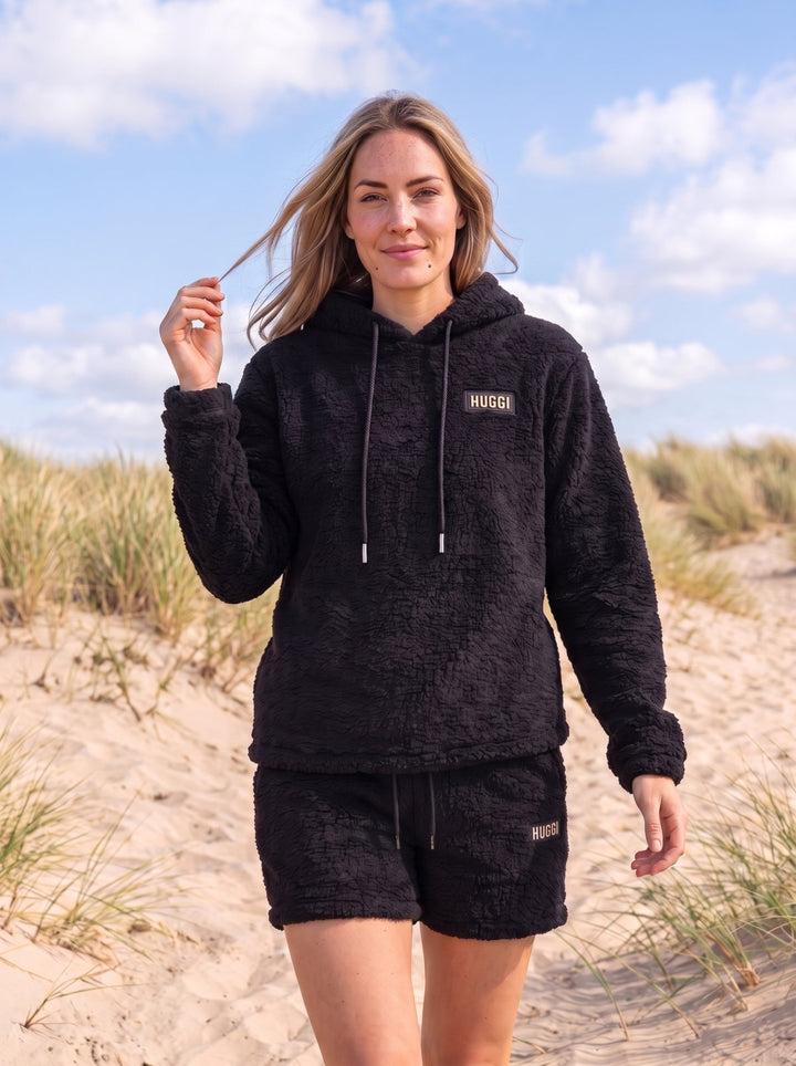 Woman in the Black Huggi Fleece Two-Piece Set walking on the beach dunes model: Emma is 5&