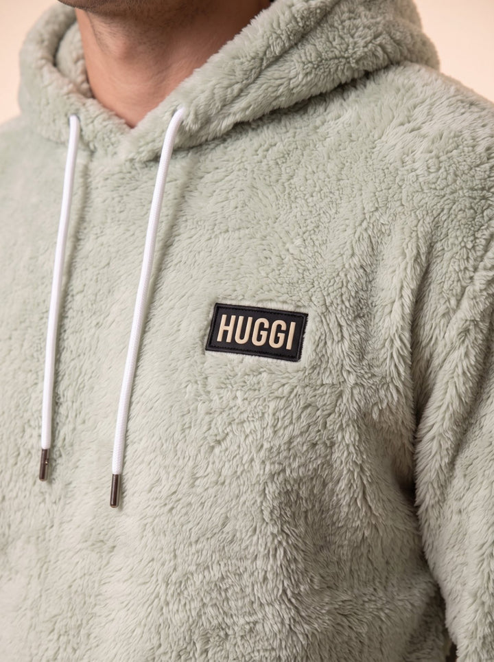 Close-up of the HUGGI logo patch on the Light Green sherpa fleece hoodie