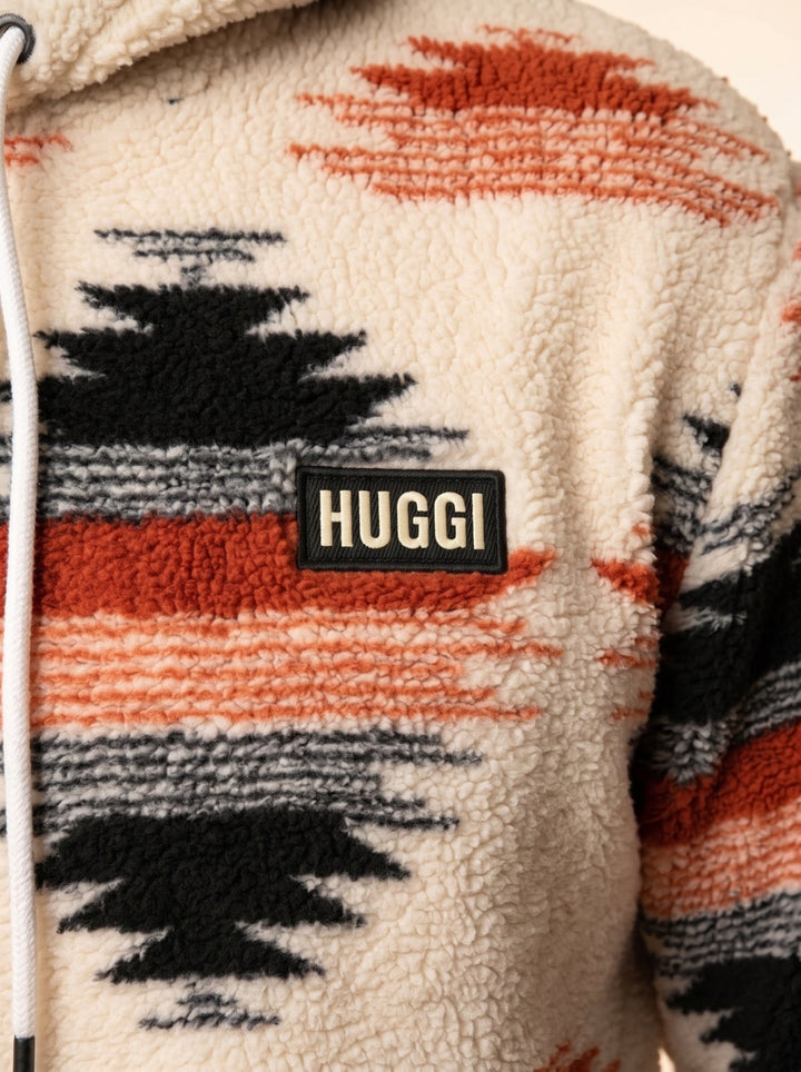 Close-up of the sherpa fleece fabric and HUGGI logo patch – White &amp; Orange Aztec print