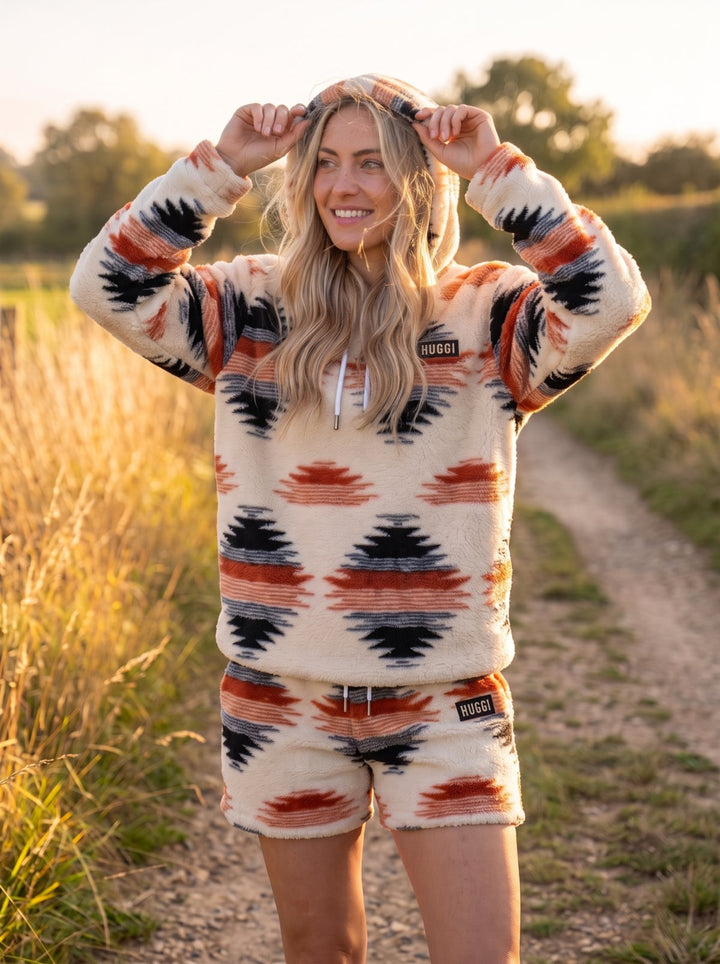 Woman outdoors in the White &amp; Orange Huggi fleece hoodie with the hood up model: Emma is 5&